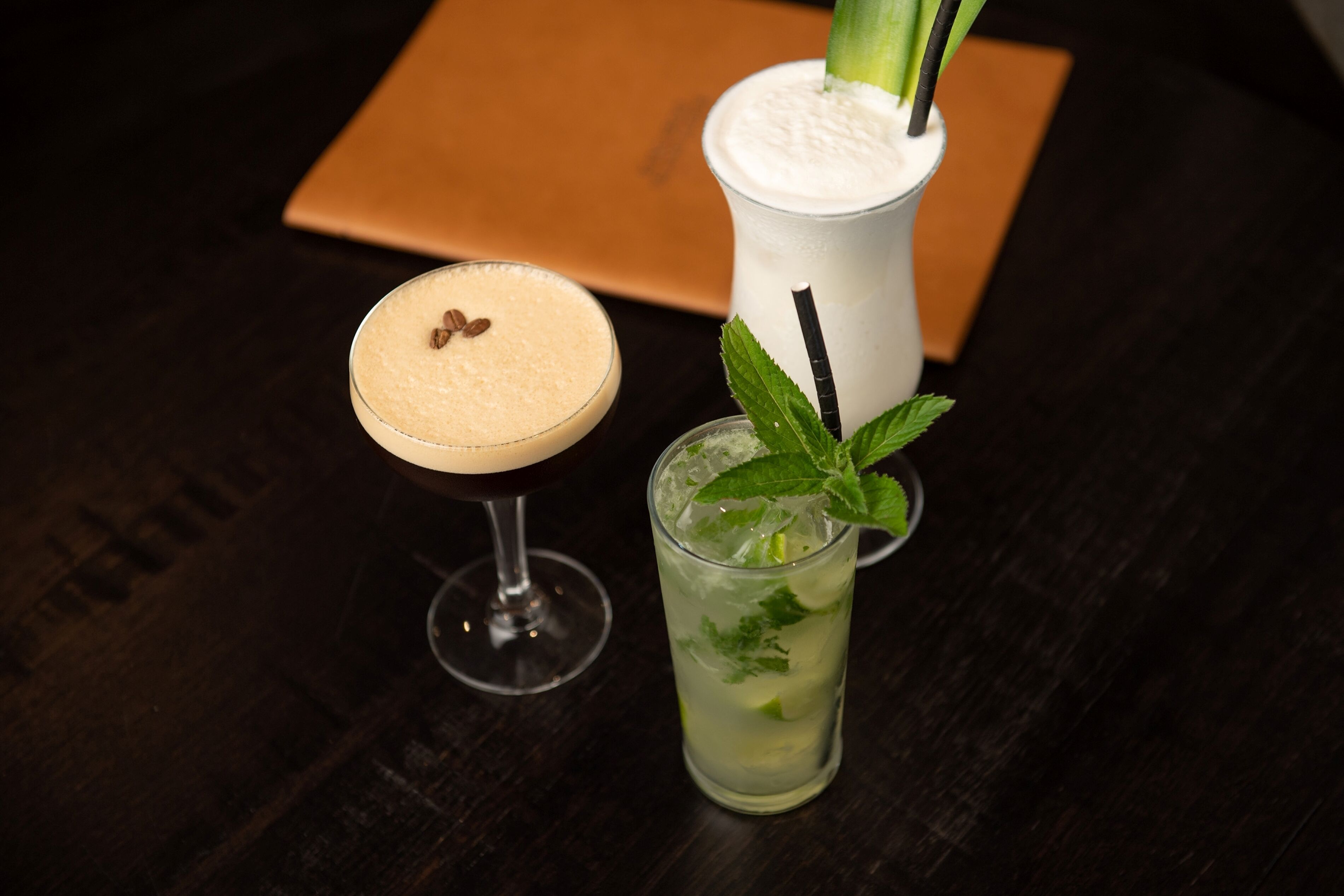 Three drinks on a dark wooden table.