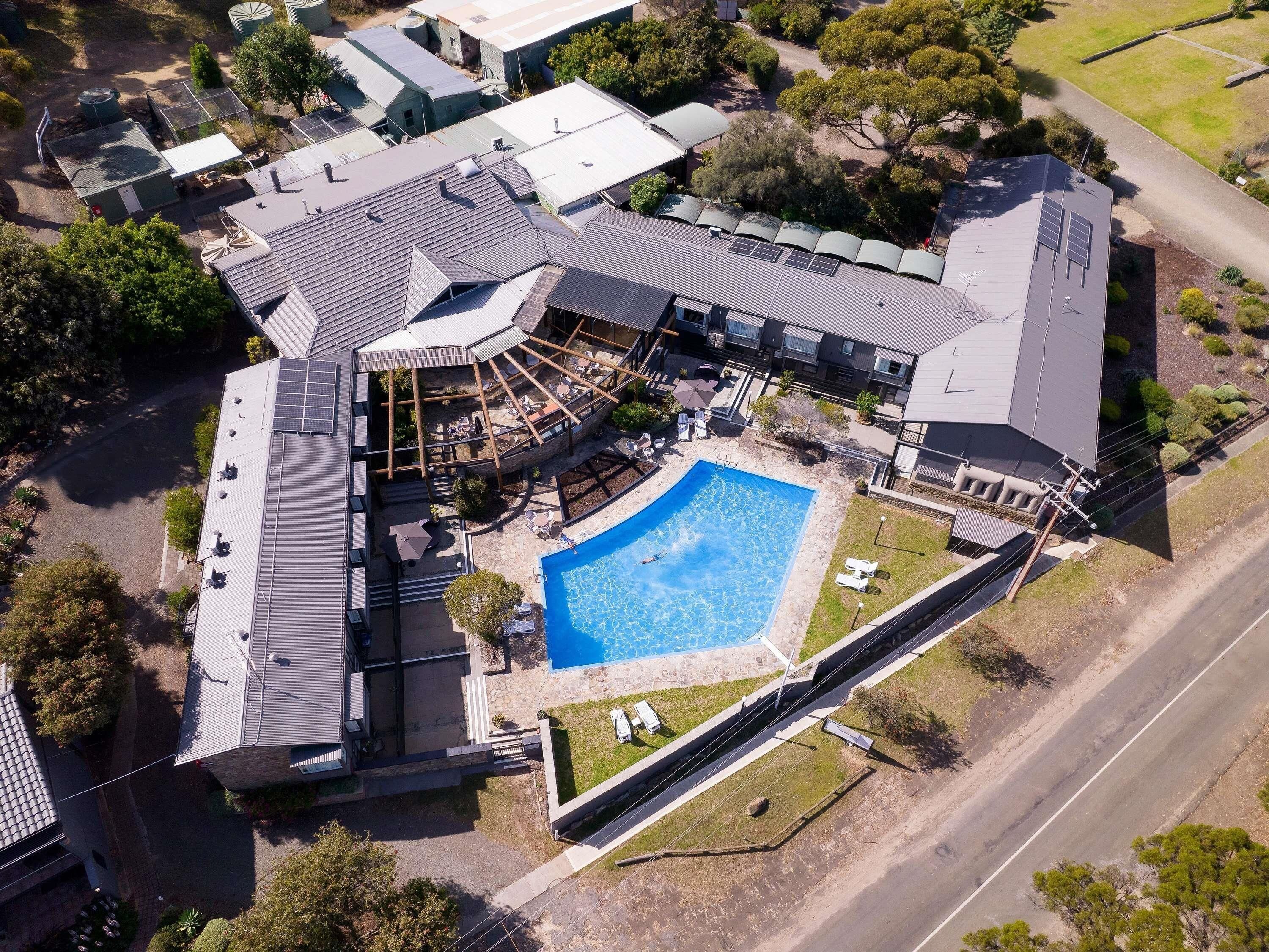 Vue aérienne d’une propriété résidentielle dotée d’une piscine, d’un espace de détente extérieur et d’un patio couvert.