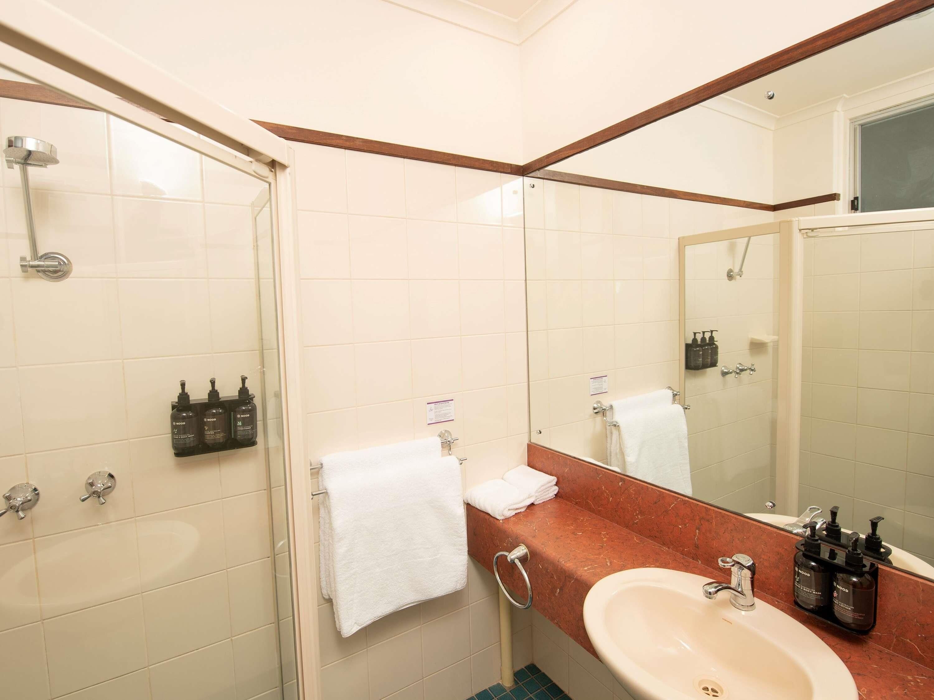 A bathroom with a shower, sink, and mirror.