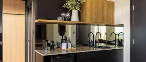 Una cocina moderna con lavavajillas integrado, un armario de madera, una encimera con un florero de hojas verdes y un espejo sobre el fregadero.