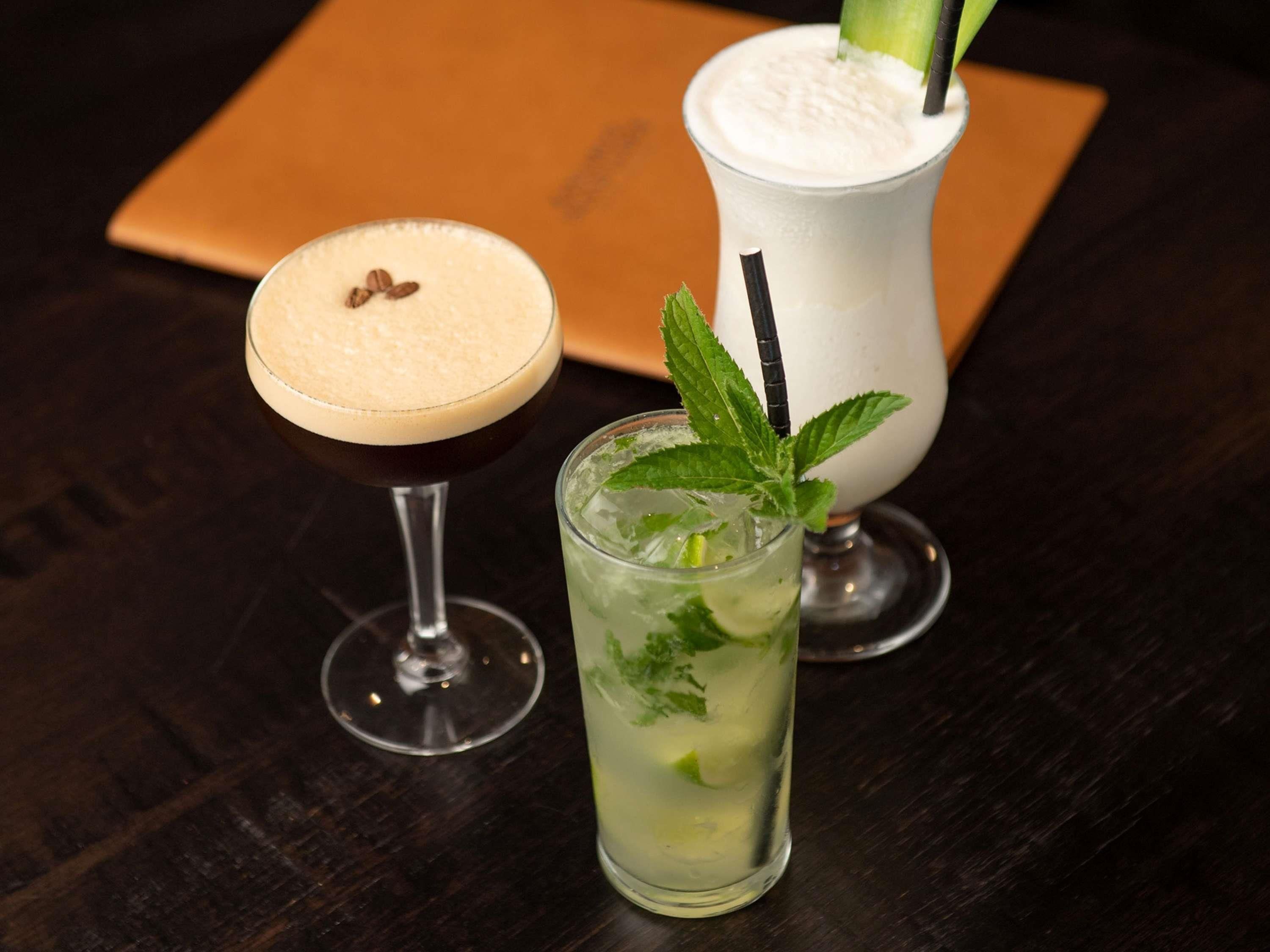Trois boissons différentes servies dans des verres, posées sur une table en bois sombre.