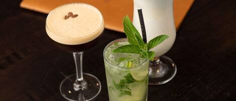Tres bebidas diferentes en vasos sobre una mesa de madera oscura.