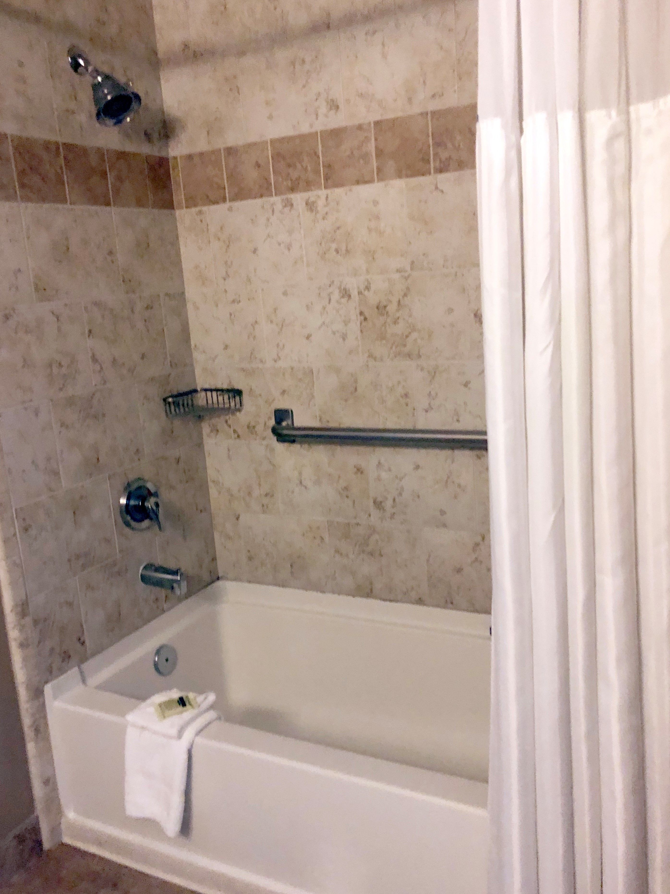 A bathroom with a bathtub, a showerhead, and a towel rack.