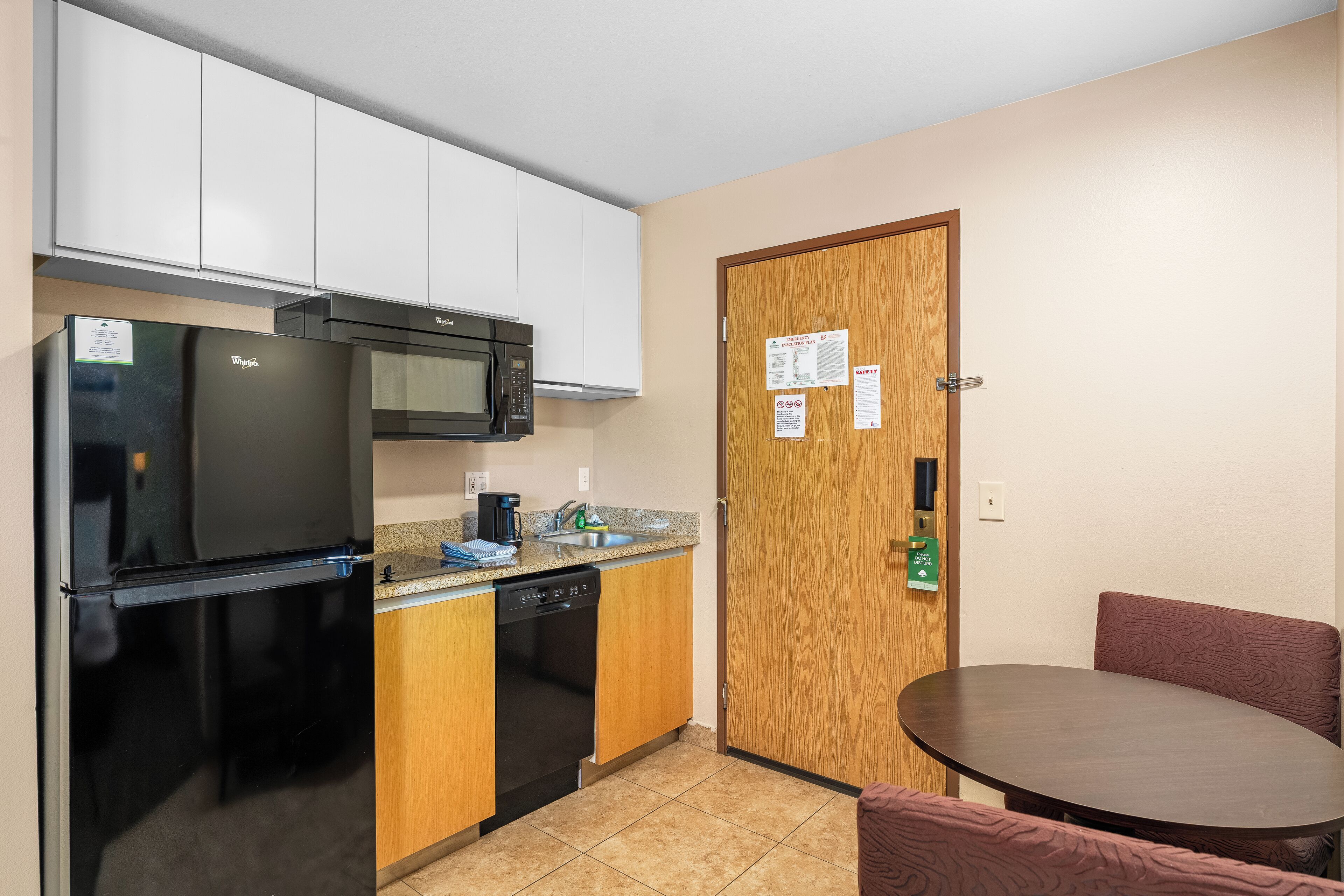 A compact kitchenette with a refrigerator, microwave, and dishwasher.