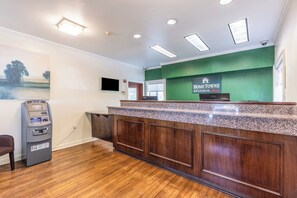 A reception desk with a green wall, a mounted television, and an ATM machine.