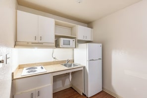 Cocina compacta con microondas, refrigerador y pileta doble.
