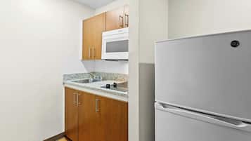 A kitchen with wooden cabinets, a white refrigerator, and a granite countertop.