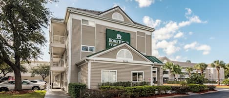 A two-story hotel with a sign reading 'HomeTown Suites.' It features a balcony on the second floor, a green roof, and a number '9435' on the facade.