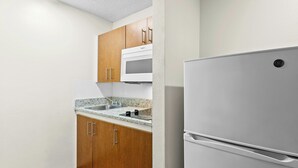 A kitchen with wooden cabinets, a white refrigerator, and a granite countertop.