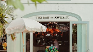 An outdoor seating area with colorful chairs and a tiki bar entrance.