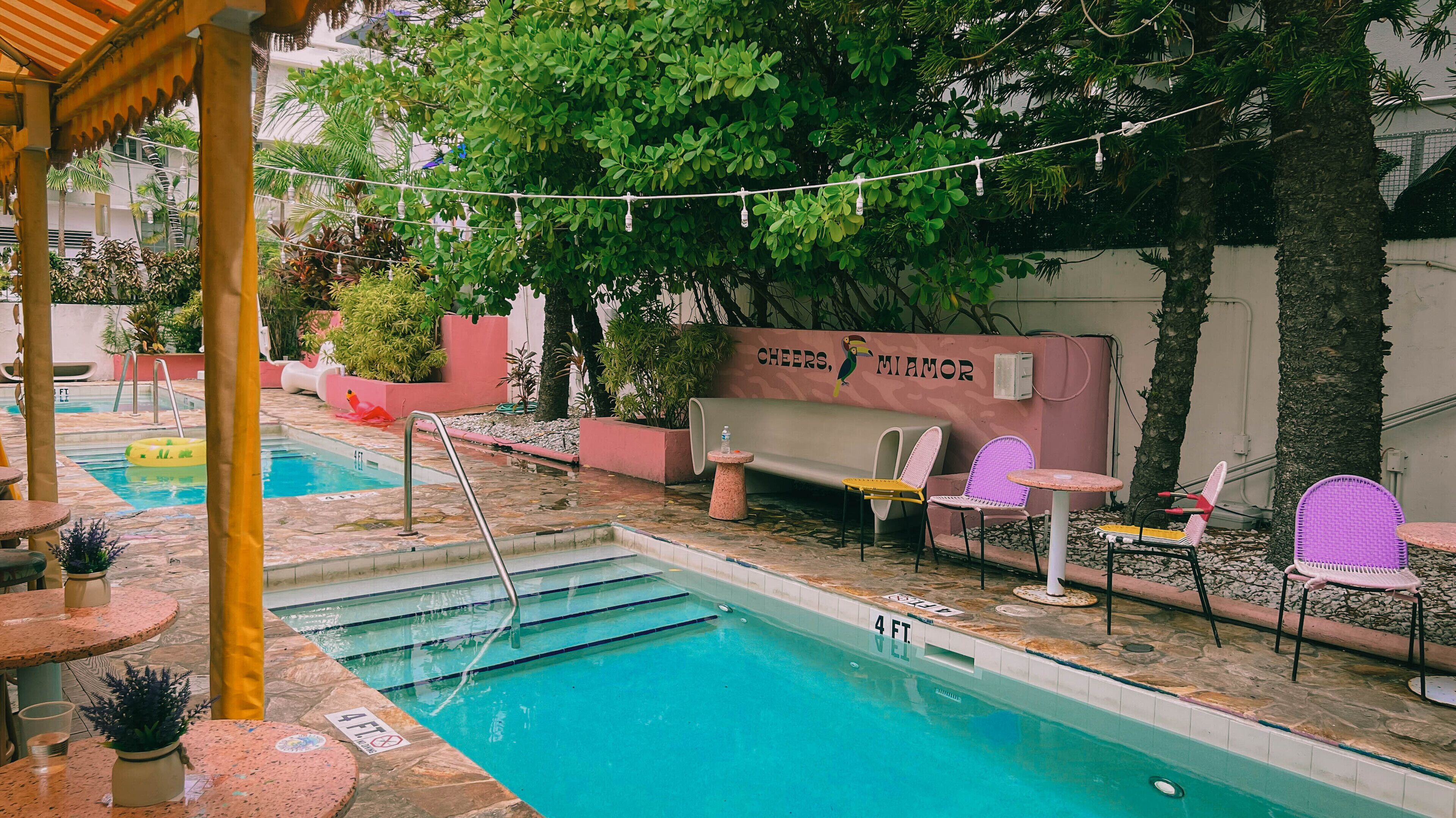 A swimming pool area with a lounge chair, a small table, and a bench.