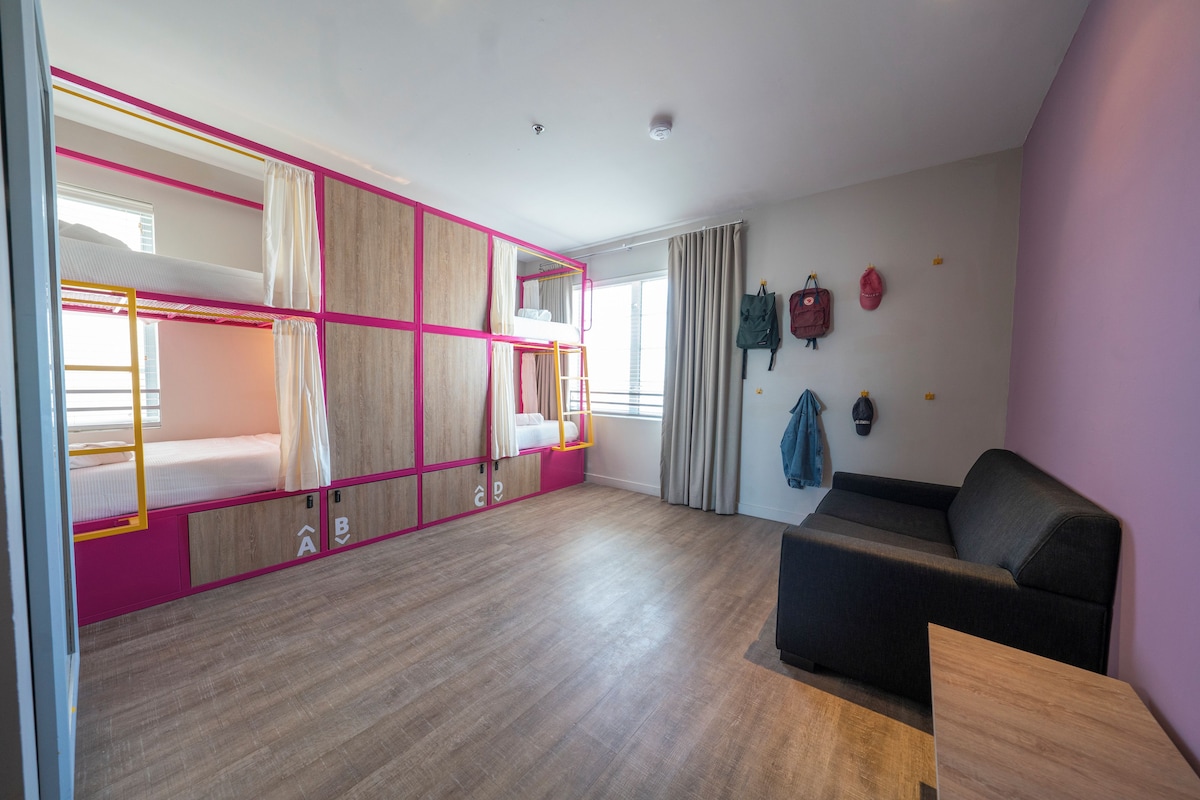 A room with bunk beds, a sofa, and a desk.
