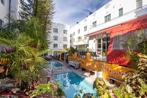 Relax by the pool surrounded by lush tropical plants and vibrant artwork.