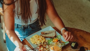 A person sitting at a table with a plate of food, a glass of orange juice, and a fork.
