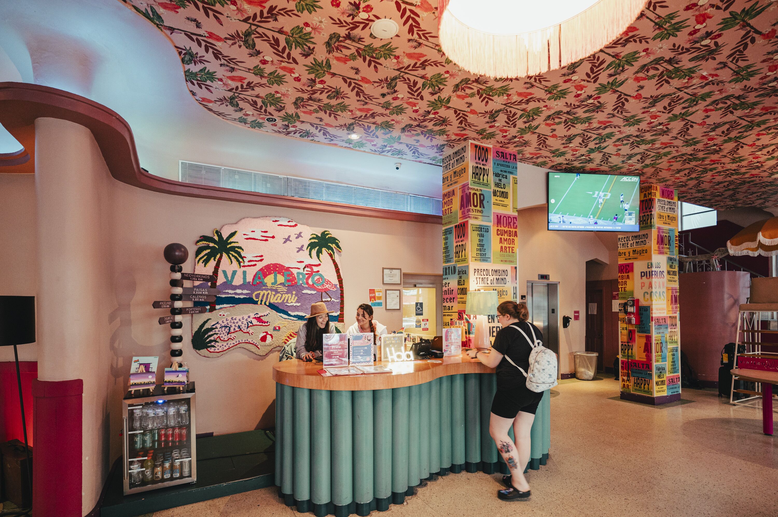 A reception area with a counter, a wall mural, a vending machine, and a television screen.