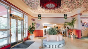 A spacious lobby with a round seating area, large windows, and a floral ceiling design.