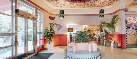 A spacious lobby with a round seating area, large windows, and a floral ceiling design.