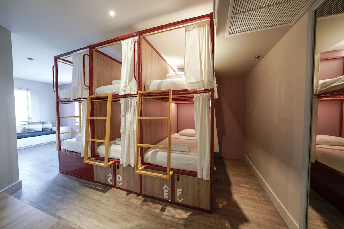 A bunk bed room with a wooden frame, white bedding, and a ladder.
