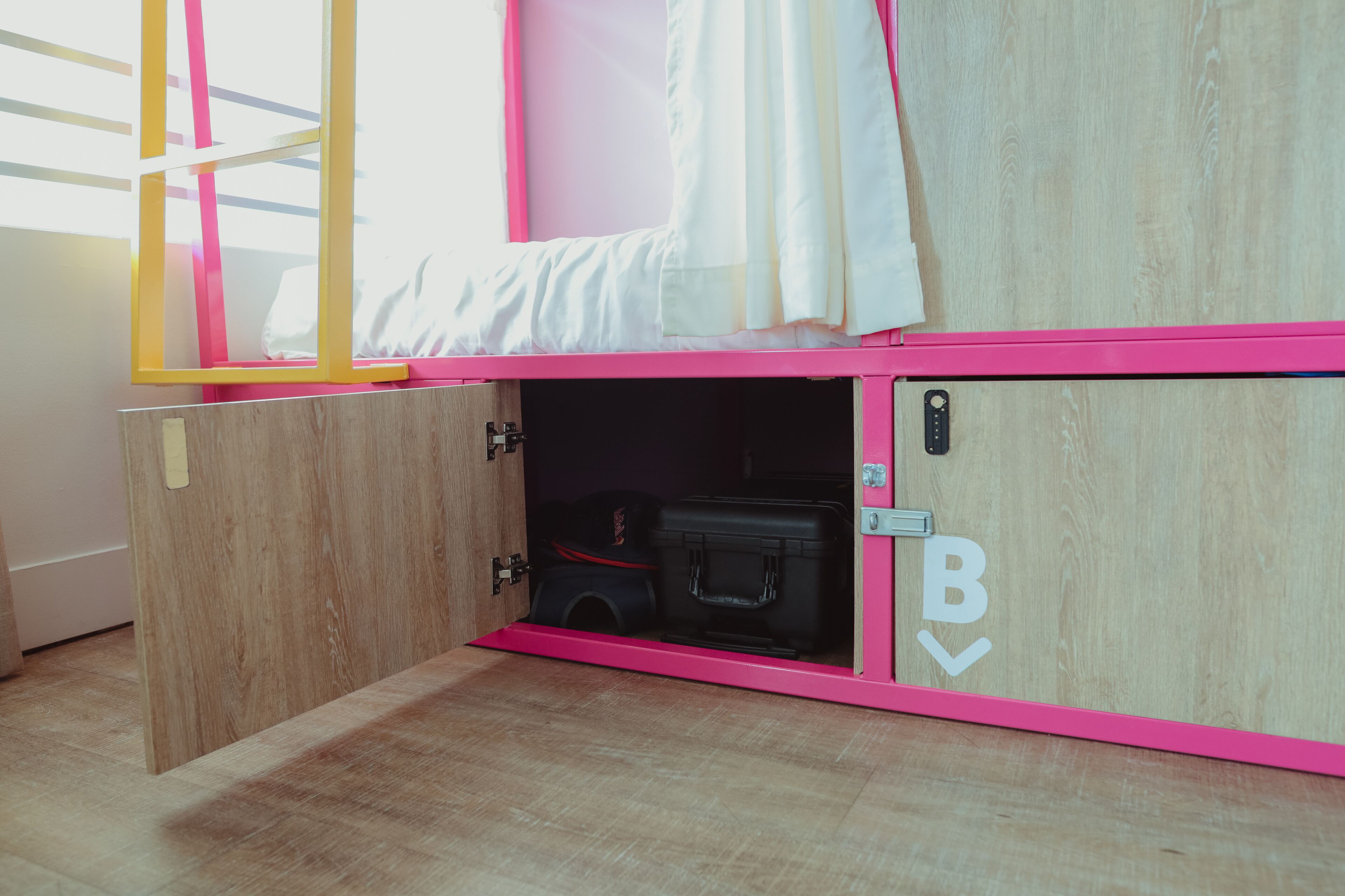 Een roze stapelbed met een opbergruimte eronder.