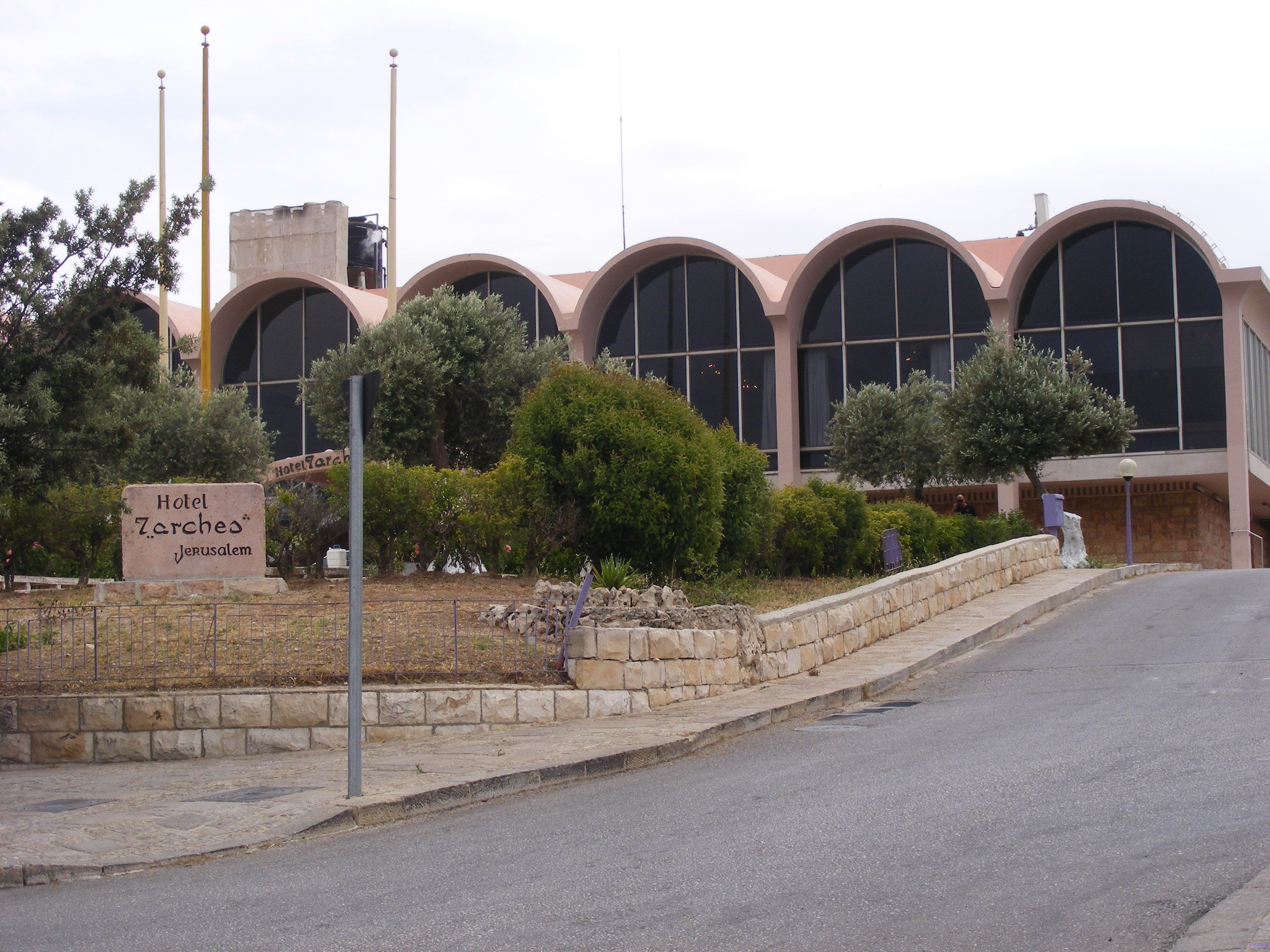 Hotel Zarchos Jerusalem with a stone facade, large arched windows, and a sign indicating its location.