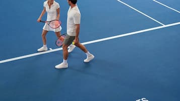 A tennis court with a net, marked lines, and the text "RACV Resorts" on the floor.