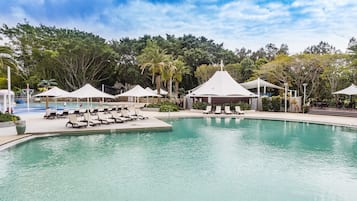 Una piscina al aire libre, sombrillas, sillones reclinables de piscina