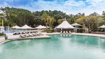 Una piscina al aire libre, sombrillas, tumbonas
