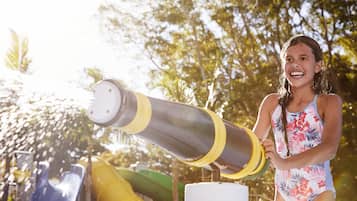 A person in a swimsuit standing next to a water slide structure.