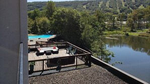 A deck with outdoor seating overlooking a lake and a pool. - Chateau Resort & Conference Center (Tannersville)