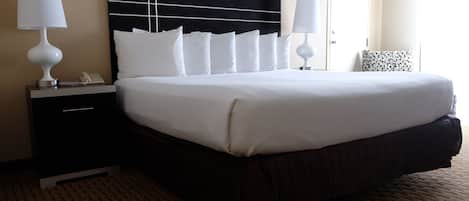 Habitación de hotel con una cama grande, dos mesitas de noche con lámparas, cabecera negra y alfombra estampada.