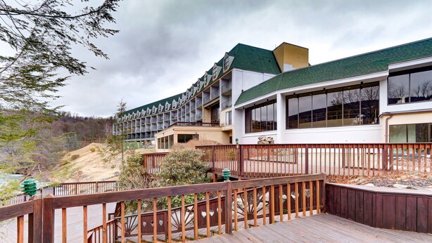 A hotel with a wooden deck, multiple balconies, and a view of the surrounding landscape. - Chateau Resort & Conference Center (Tannersville)