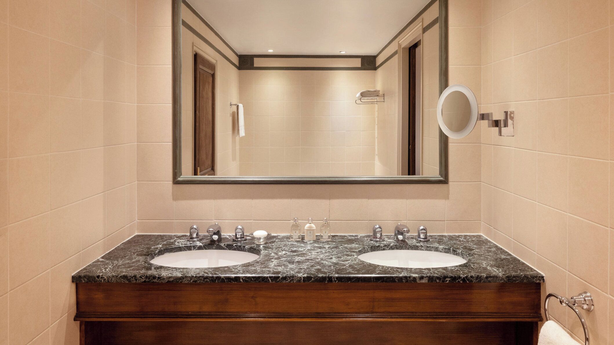 Une salle de bain avec deux lavabos, un grand miroir et un porte-serviettes.