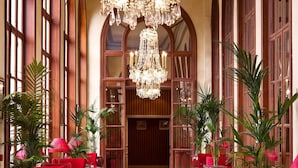 A hotel lobby with a grand chandelier, red seating, and tall windows. - Hôtel Barrière Le Royal Deauville (Deauville)