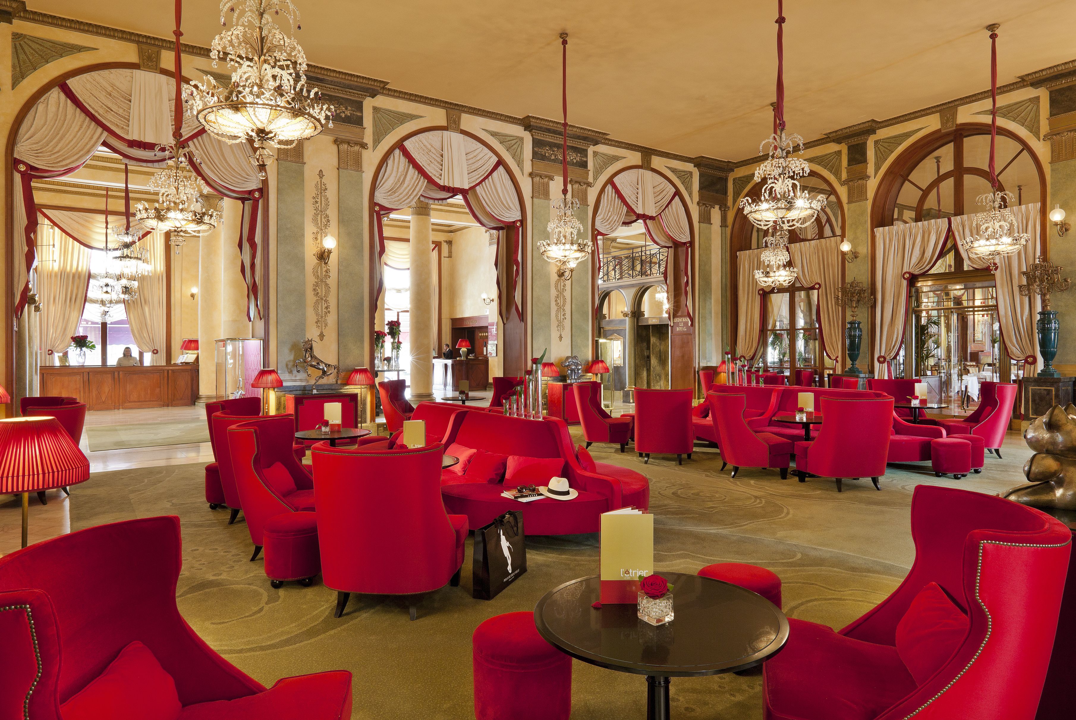 Un hall d’entrée spacieux, doté de sièges rouges, de lustres et d’un comptoir d’accueil.
