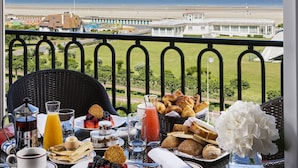 A breakfast table with pastries, fruits, and beverages, overlooking a beach and ocean view. - Hôtel Barrière Le Royal Deauville (Deauville)