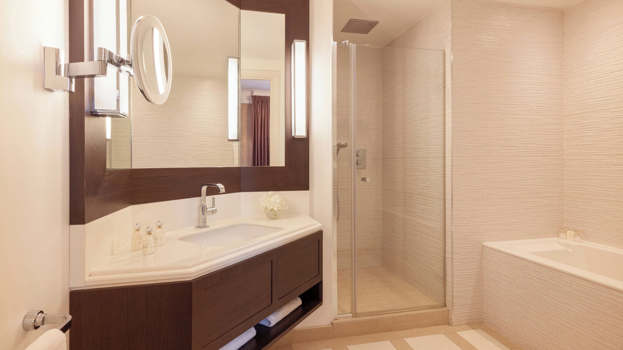 A modern bathroom with a large mirror, a sink, a shower, and a bathtub.
