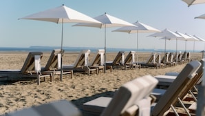 A row of beach chairs and umbrellas on a sandy beach. - Hôtel Barrière Le Royal Deauville (Deauville)