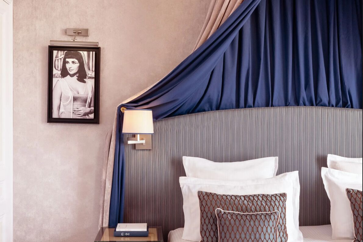 A neatly arranged hotel room with a bed, a bedside table with a lamp, and a framed picture on the wall.