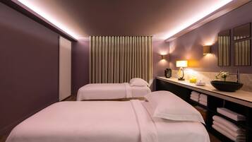 Two single beds with white linens, a bedside table and lamp, and a large mirror.