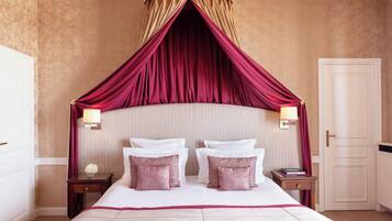 A bedroom with a four-poster bed, two bedside tables, and a door.
