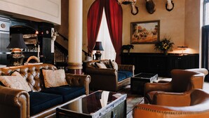 A traditional lobby with leather furniture, a fireplace, and mounted animal heads.