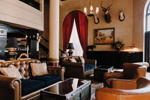A traditional lobby with leather furniture, a fireplace, and mounted animal heads. - The Driskill, in The Unbound Collection by Hyatt (Austin)