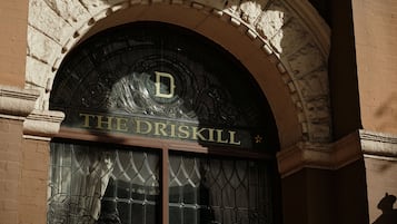 An arched entrance with the sign "THE DRISKILL" above a window with decorative ironwork.