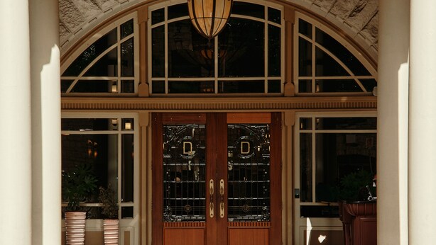 A grand entrance with a large arched doorway, a chandelier, and a set of double doors with glass panels.