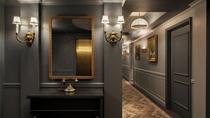 A hallway with a mirror, wall sconces, a fireplace, and a patterned carpet.