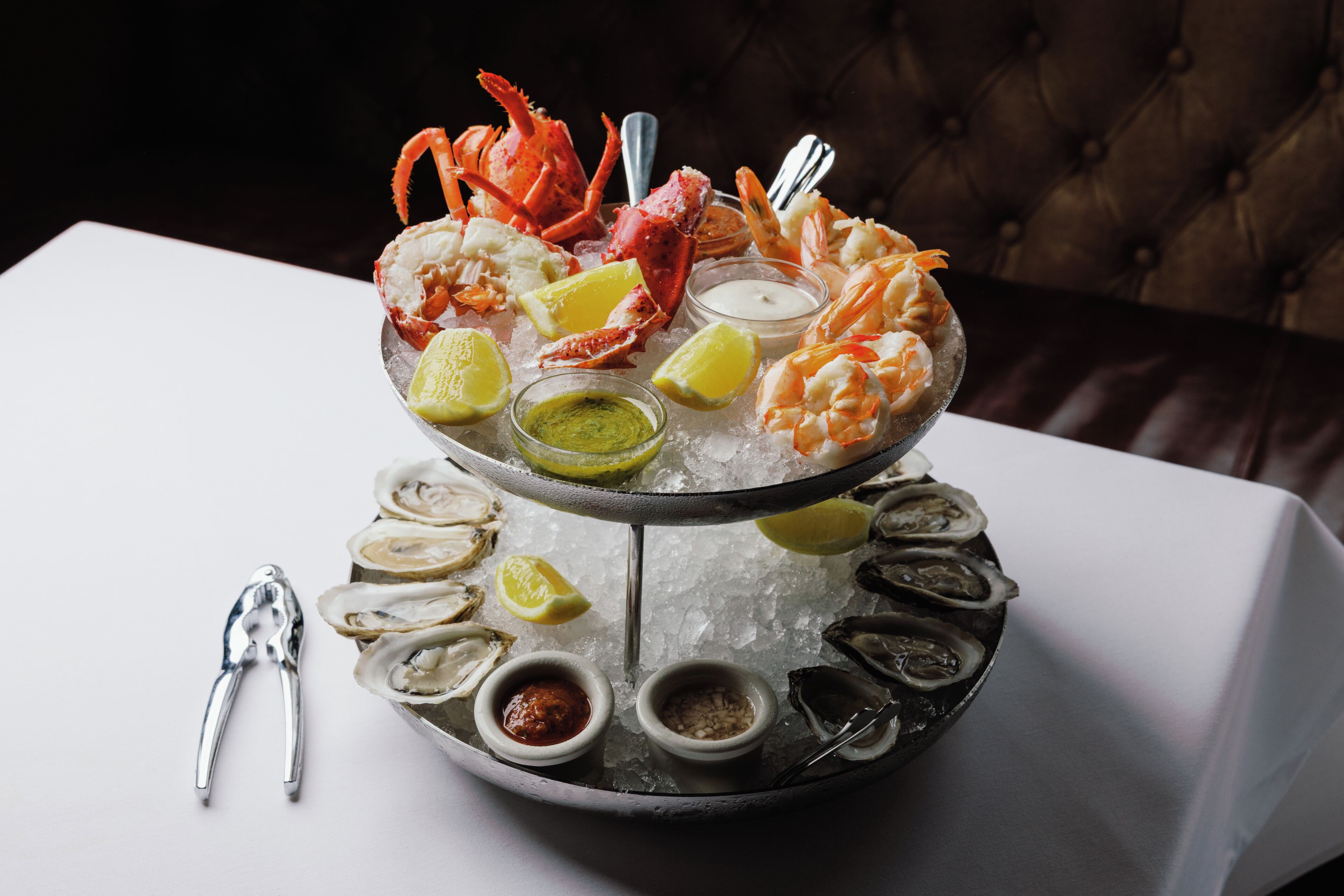 A seafood platter on a bed of ice with various seafood, lemon slices, and condiments.