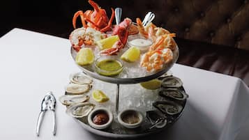 A seafood platter on a bed of ice with various seafood, lemon slices, and condiments.