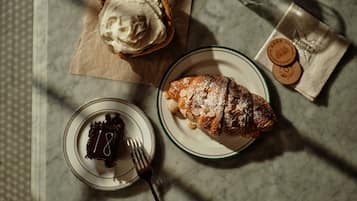 A dessert plate with a pastry, a slice of cake, and a glass of water on a marble table.
