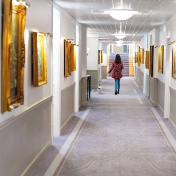 Stunning corridor lined with artwork, leading to a grand staircase. at The Driskill, in The Unbound Collection by Hyatt