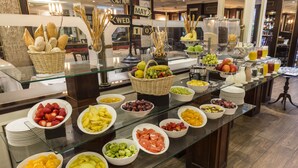 A buffet with various fruits and vegetables, including bowls of strawberries, grapes, and oranges.